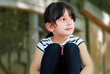 Ayan, ein kleines Flüchtlingsmädchen aus Aserbaidschan, schaut verträumt durch die Gegend.