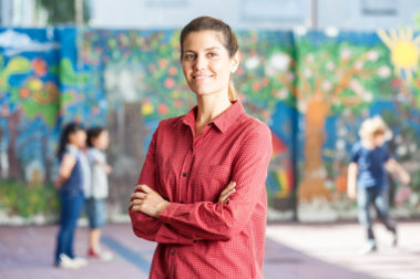 Female teacher happy with her classroom playing in courtyard. Portrait einer Erzieherin.