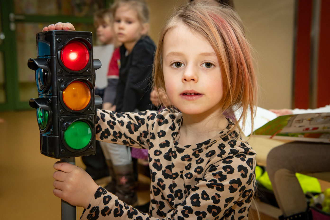 Ein Mädchen hält eine kleine Ampel in der Hand und übt damit die Verkehrsregeln.