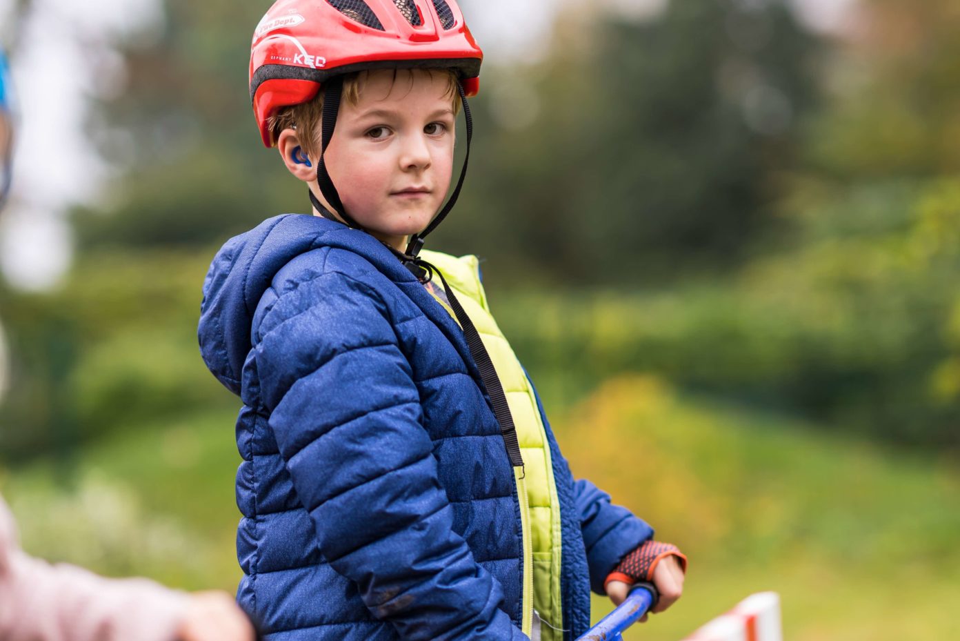 Ein Junge steht auf seinem Roller und guckt in die Kamera.