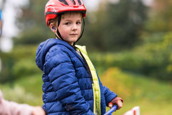 Ein Junge steht auf seinem Roller und guckt in die Kamera.