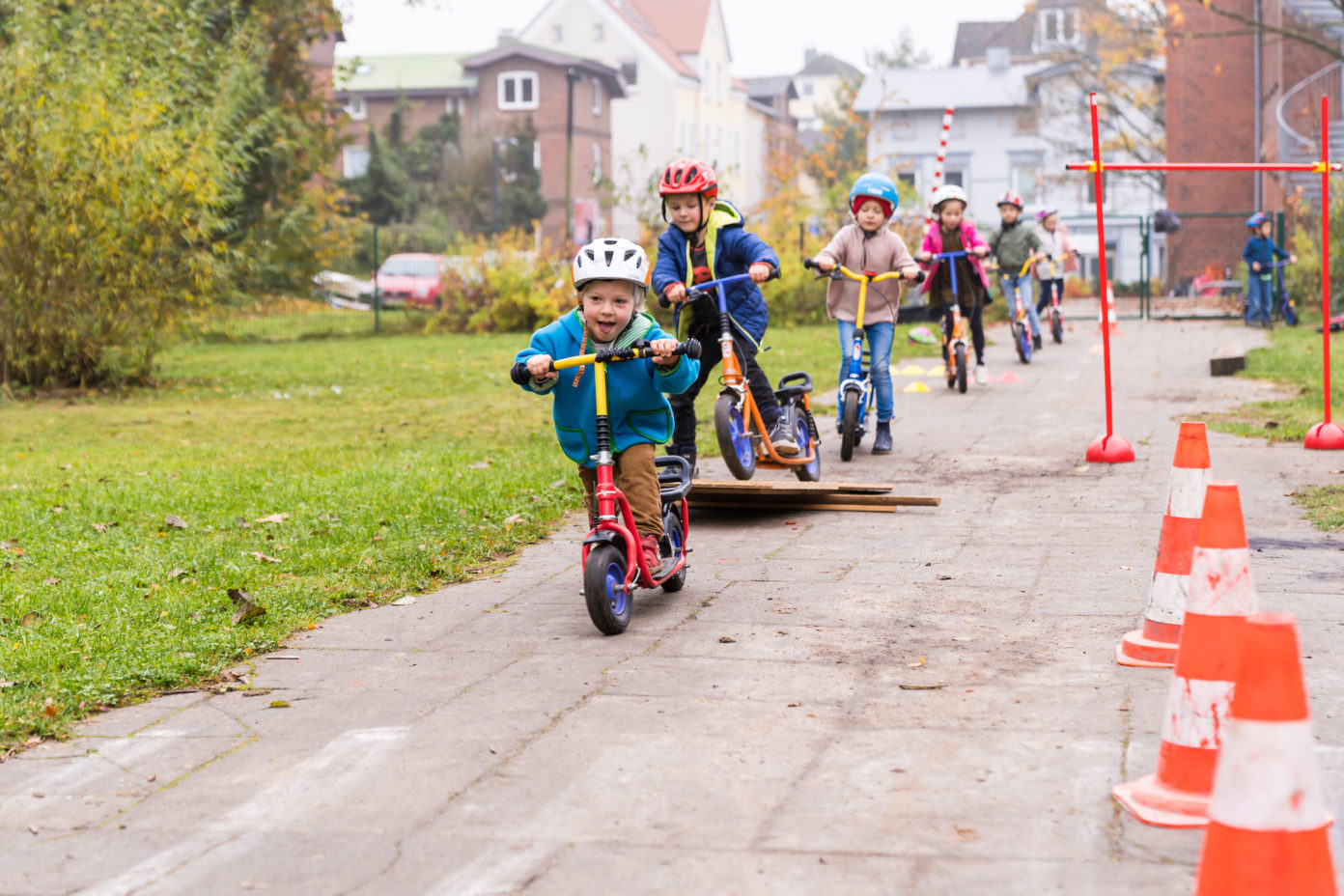 Mehrere Kinder fahren auf ihren Rollern durch einen Parcours.