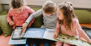 Kinder schauen sich Bücher an und recherchieren in einem Tablet Kinder schauen sich Bücher an und recherchieren in einem Tablet