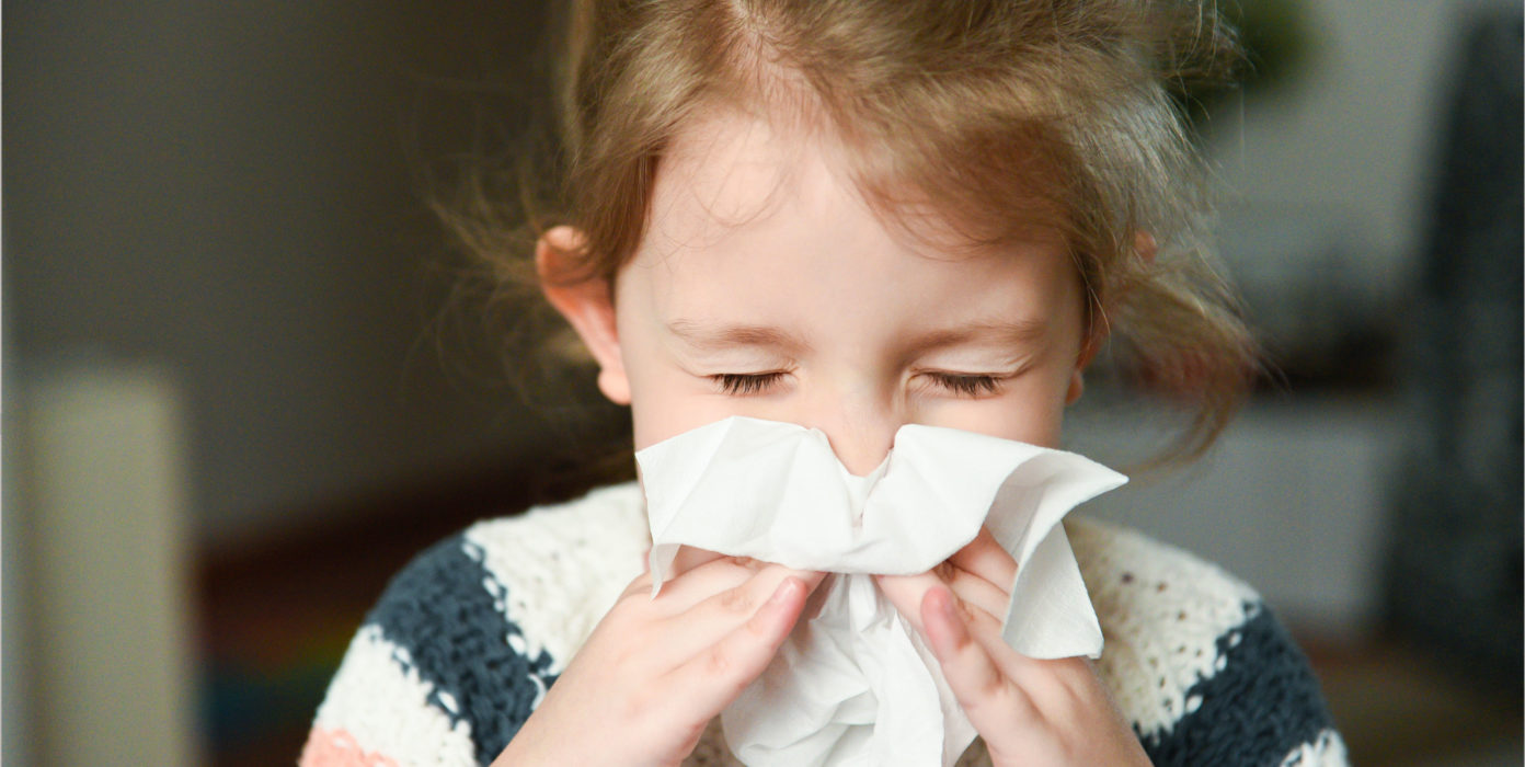 Kind schnauzt sich die Nase.