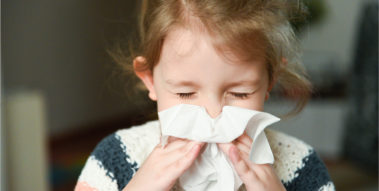 Kind schnauzt sich die Nase.