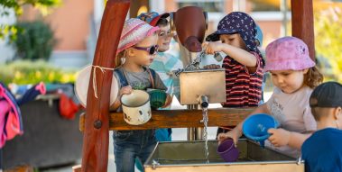 Mehrere Kinder spielen an einem Wasserlauf