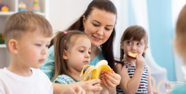 Erzieherin isst mit Kindern Obst