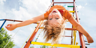 Ein Kind hängt kopfüber an einem Klettergerüst.