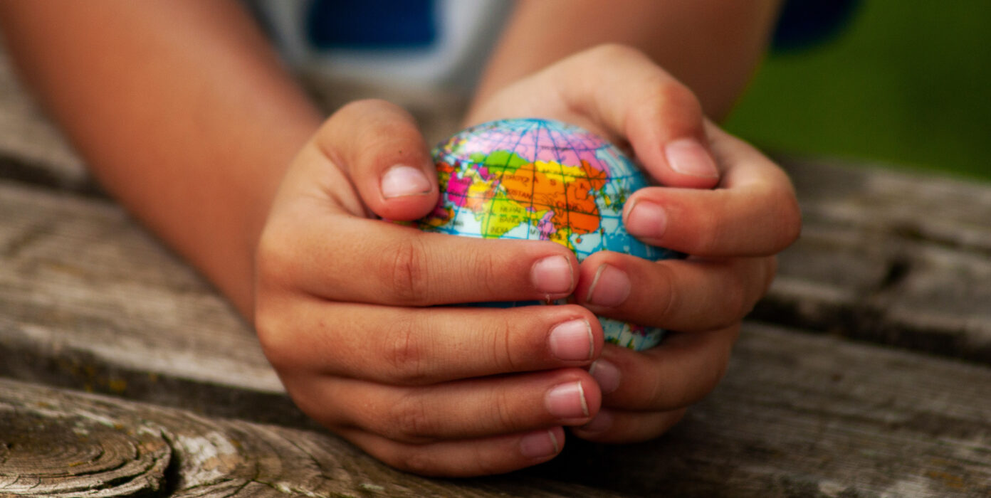 Zwei Hände halten einen kleinen Globus.