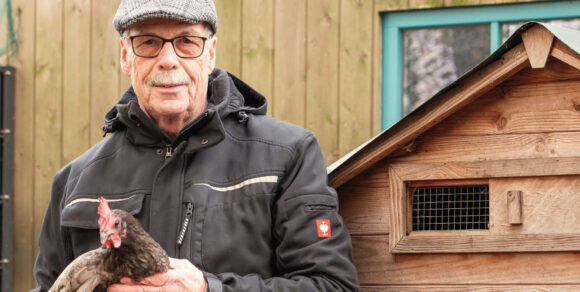Berndfried Baals mit einem Huhn vor dem Stall.